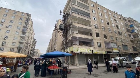 Faciaya davetiye: Ağır hasarlı bina önünde semt pazarı