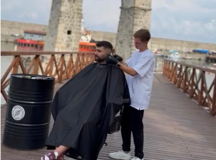 Genç kuaför müşterisini deniz manzarası eşliğinde tıraş etti